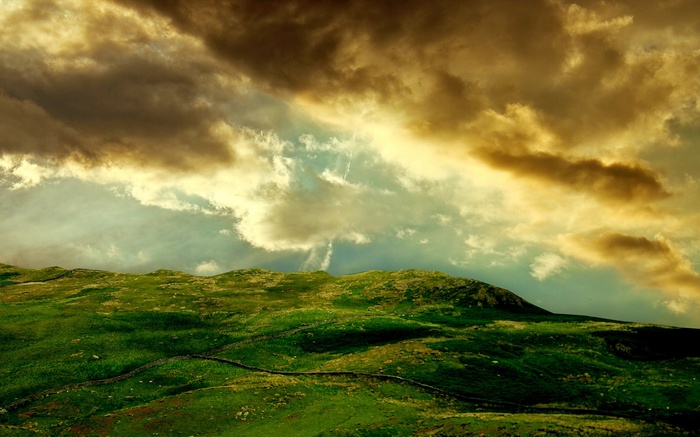 Green rolling hills under dramatic cloudy sky
