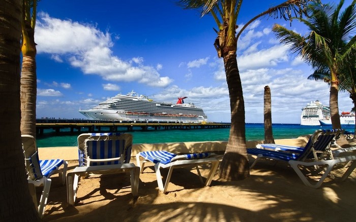 Cruise ships docked at a tropical resort with beach chairs