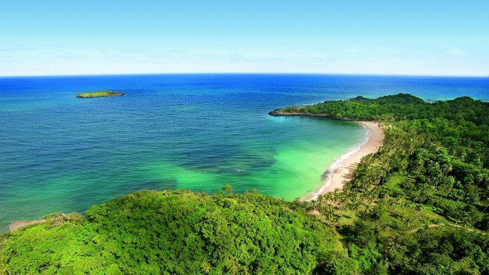 Tropical bay with lush green hills and a small island