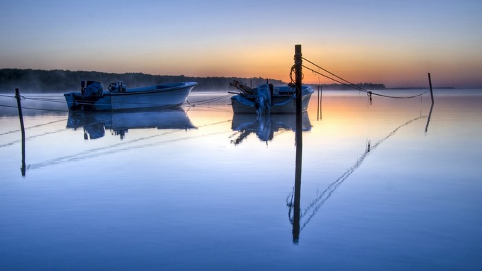 Two boats moored on a calm lake at sunrise