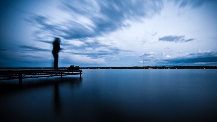 Person on a dock over a calm lake at dusk