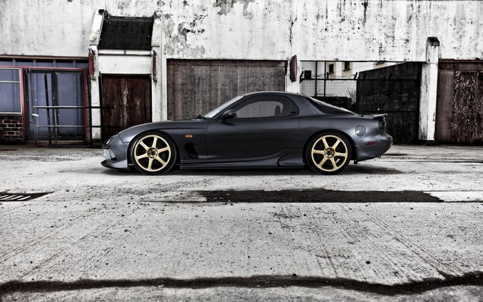 Dark grey Mazda RX-7 with gold wheels parked outdoors