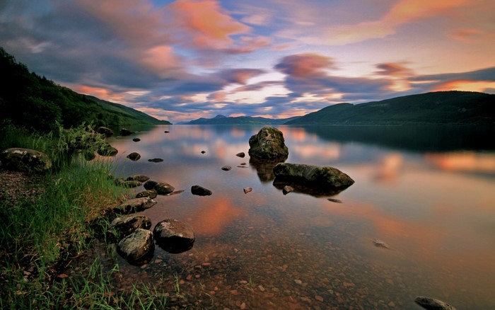 Sunset over a rocky lake shore with mountains