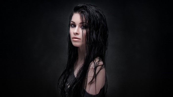 Model with wet black hair in a dark setting