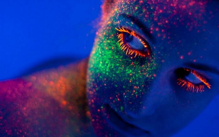 Close up of a woman's face with neon body paint