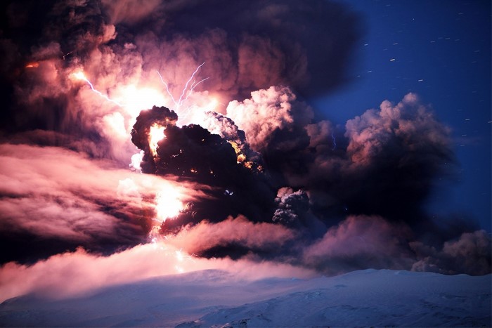 Volcanic eruption with lightning over snowy landscape