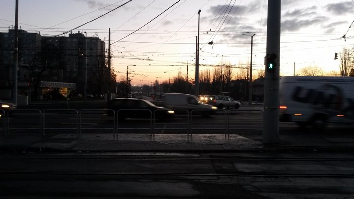 Street traffic at sunset with buildings and overhead wires