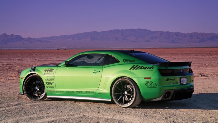 Green Chevrolet Camaro with racing decals in desert landscape