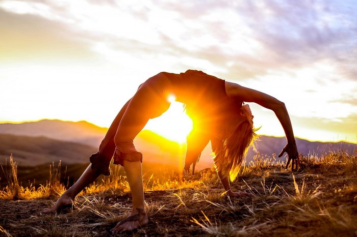 Woman doing yoga during sunrise over mountains