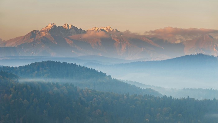 Misty mountain range at sunrise with snow-capped peaks
