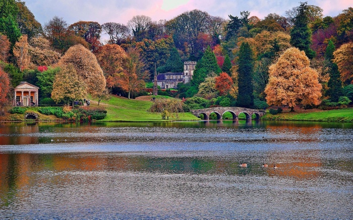 Autumn landscape with lake, bridge, and classical buildings