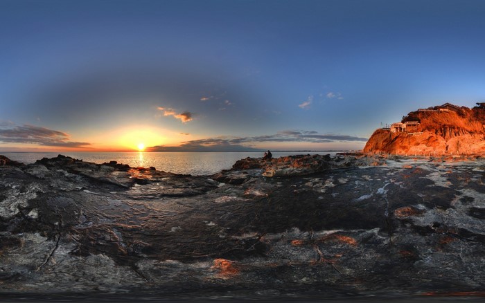 Sunset over rocky coast with cliffside houses