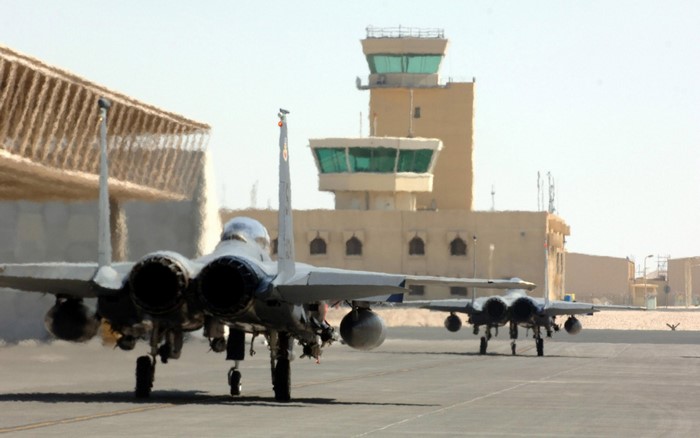 Two F-15 Eagle fighter jets on tarmac with control tower