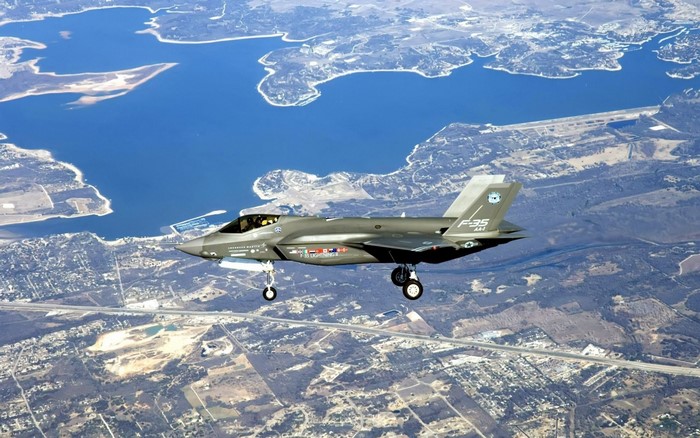 Lockheed Martin F-35A Lightning II flying over a lake and landscape