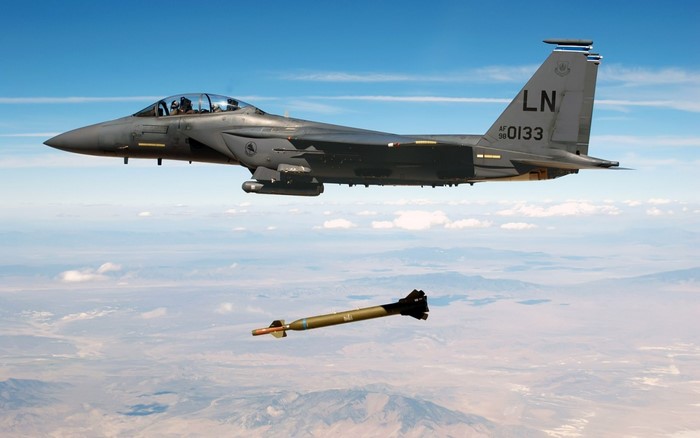 F-15E Strike Eagle releasing a munition over a desert landscape