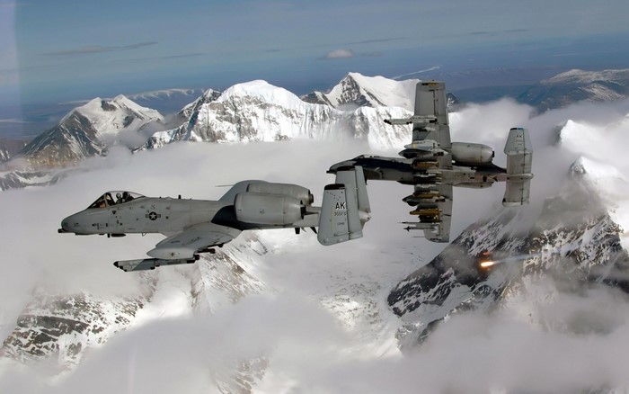 Two A-10 Thunderbolt II aircraft flying over snowy mountains