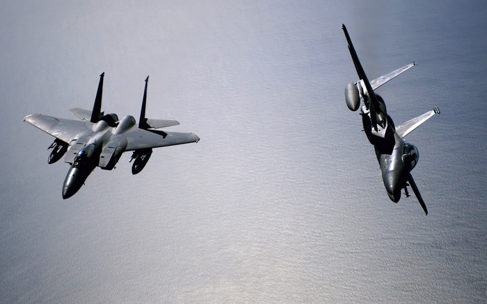 Two fighter jets flying over the ocean