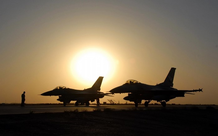 Two F-16 fighter jets on tarmac at sunset