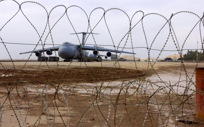 Lockheed C-5 Galaxy aircraft on tarmac behind barbed wire