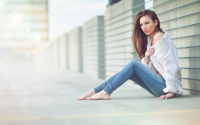 Woman in white shirt and jeans sitting outdoors