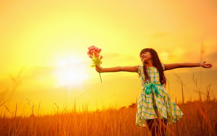 Girl holding flowers in a field at sunset