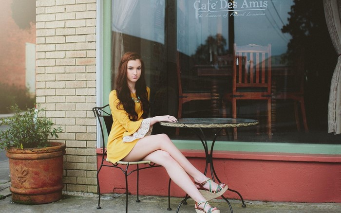 Woman in yellow dress sitting at cafe table