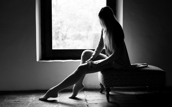 Woman in knee-high socks sitting by a window