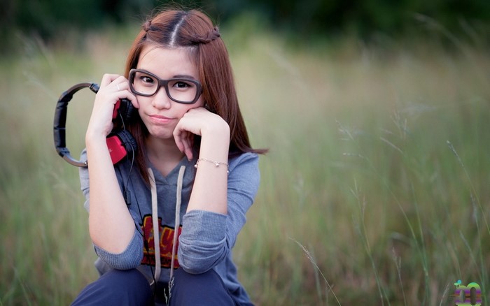 Young woman with headphones and glasses in a field
