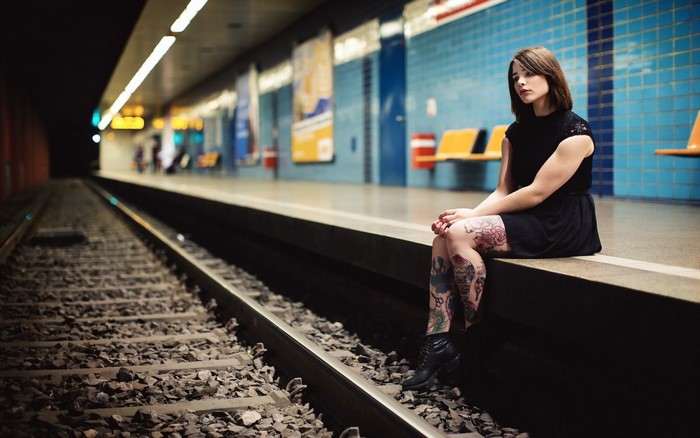 Woman with tattoos sitting at a train station