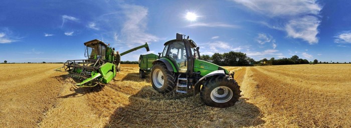 Tractor and combine harvester in a wheat field