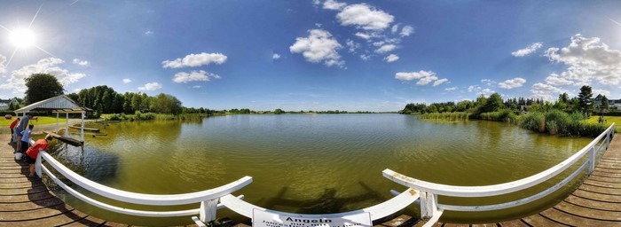 People on a wooden pier by a lake on a sunny day