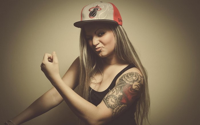 Woman wearing a Miami Heat hat and tank top with tattoos