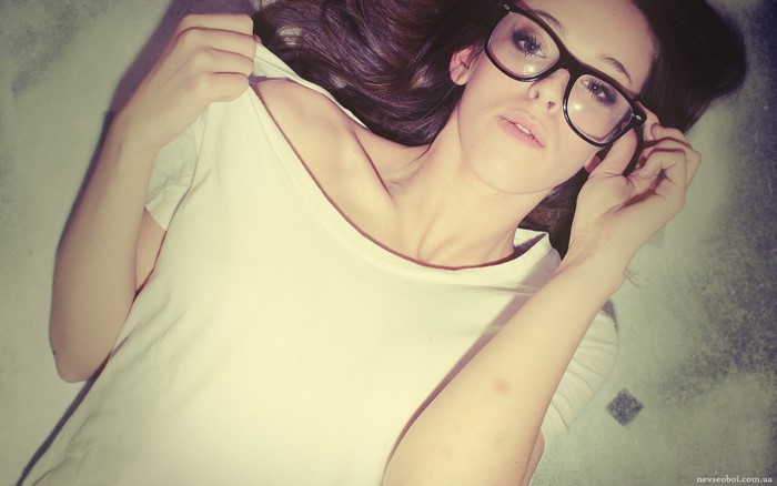 Woman with glasses lying down, pulling shirt