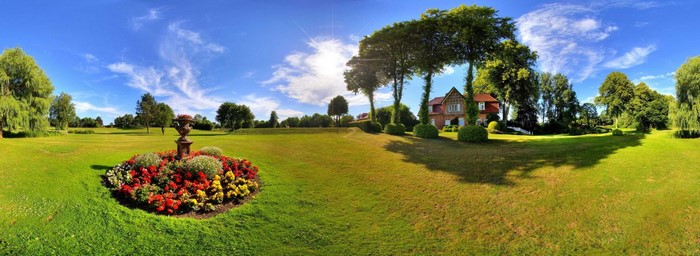 Panoramic view of a park with a flower bed and a house