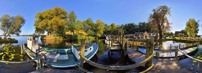 Boats docked at a scenic waterfront with trees and buildings