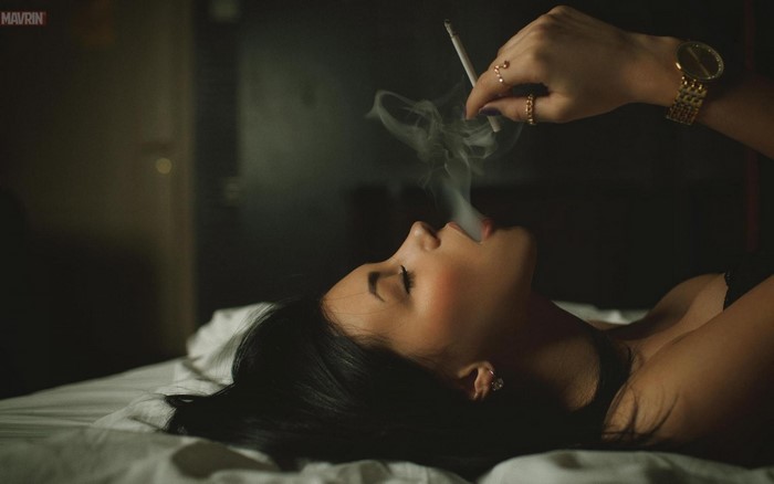 Woman lying down smoking a cigarette