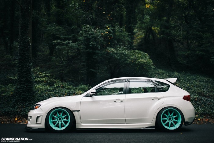 White Subaru Impreza with Teal Wheels in Forest