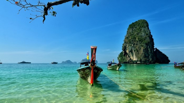 Longtail boats in a tropical bay with a large rock island