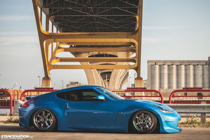 Blue Nissan 370Z sports car parked under a yellow bridge