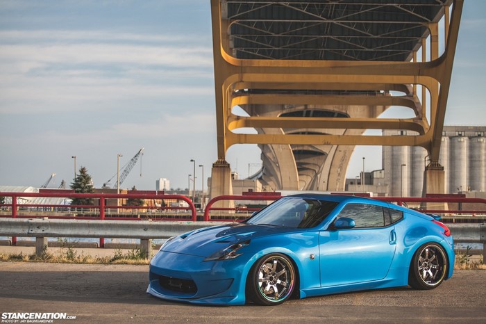 Blue Nissan 370Z sports car parked under a yellow bridge