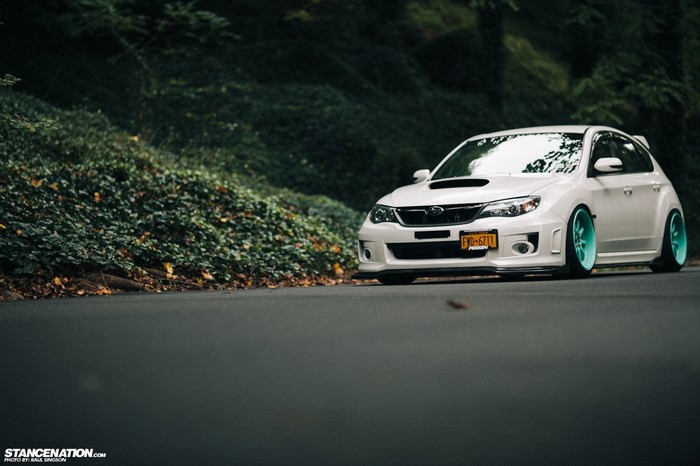 White Subaru Impreza with Teal Wheels on Road