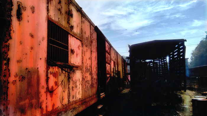 Abandoned rusty train cars under a cloudy sky