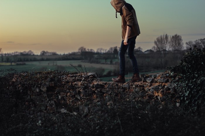Person walking on a stone wall at sunset