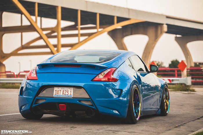 Blue Nissan 370Z with custom wheels parked under a bridge