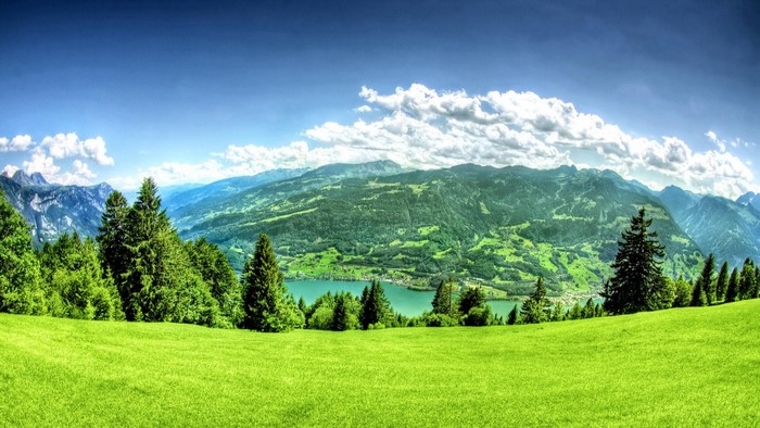 Green valley with lake and mountains under blue sky