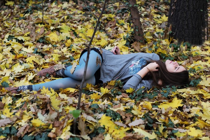 Woman lying in autumn leaves in a forest