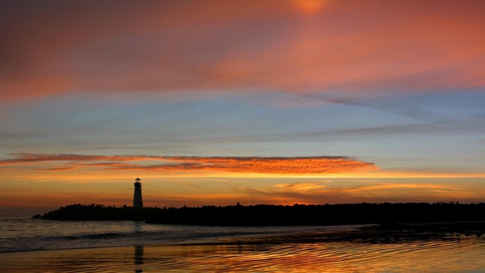 Silhouette of a lighthouse at sunset over the ocean