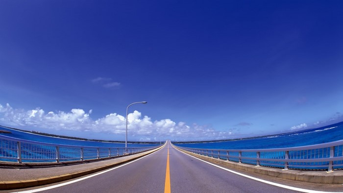 A long bridge over the ocean under a blue sky