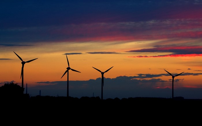 Wind turbines silhouetted against a colorful sunset sky