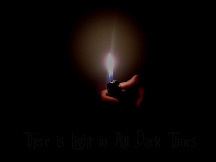 Hand holding a lighter with a flame in the dark